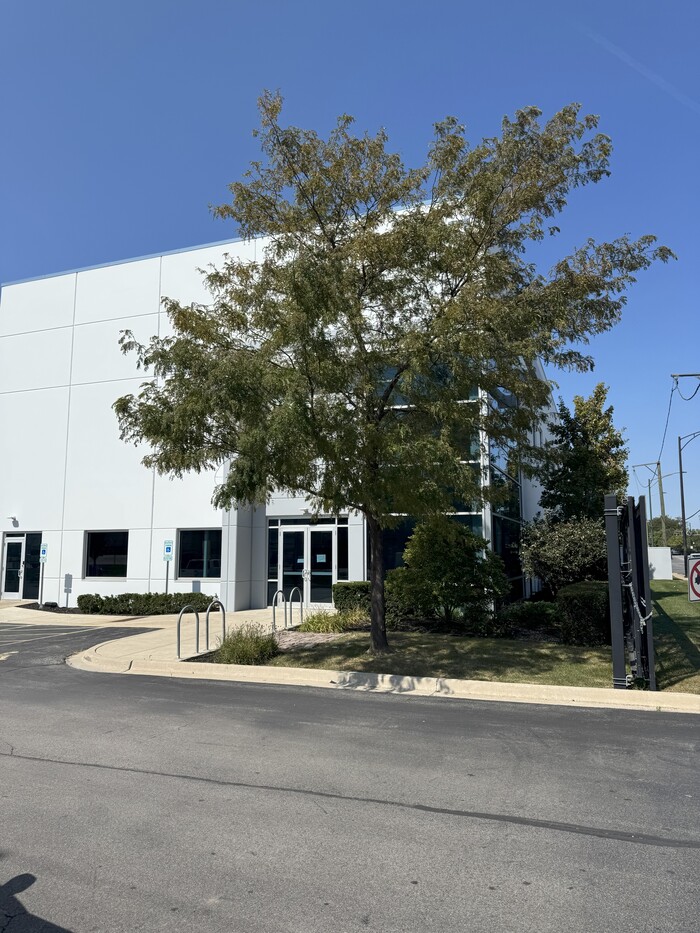 Commercial warehouse exterior with accessible parking spaces, white panel facade, and large entrance doors.